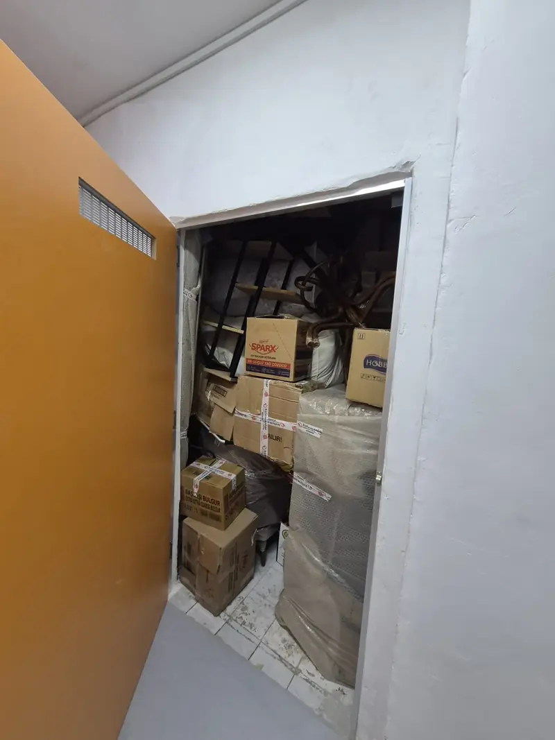 Kapısı açık bir depolama bölmesinde kolilenmiş ve sarılmış eşyalar